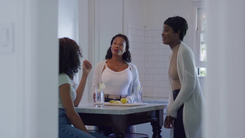 Three women smiling and chatting around a kitchen counter