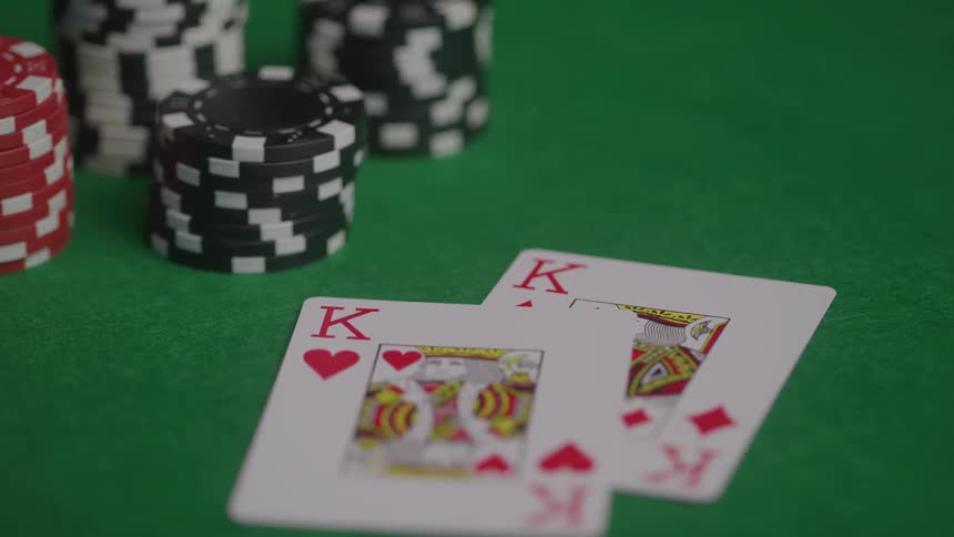 Closeup of playing cards and poker chips on green felt