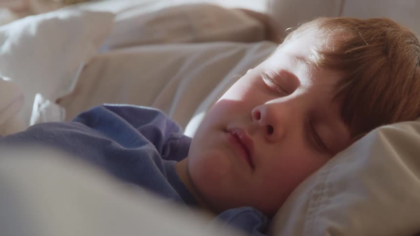 A young boy sleeps soundly in a comfortable bed