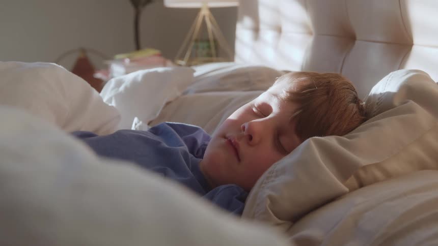 Child sleeping peacefully on a bed in a bedroom