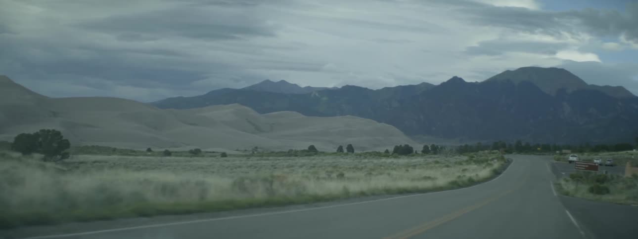 A vehicle drives on a road in the mountains