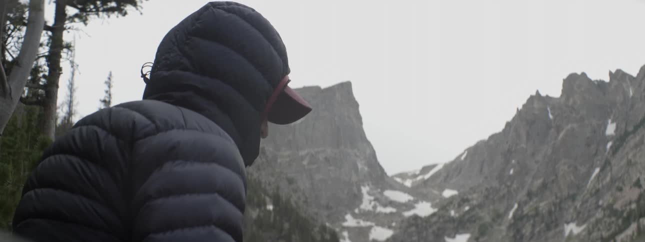 A man wears a coast in the snowy mountains