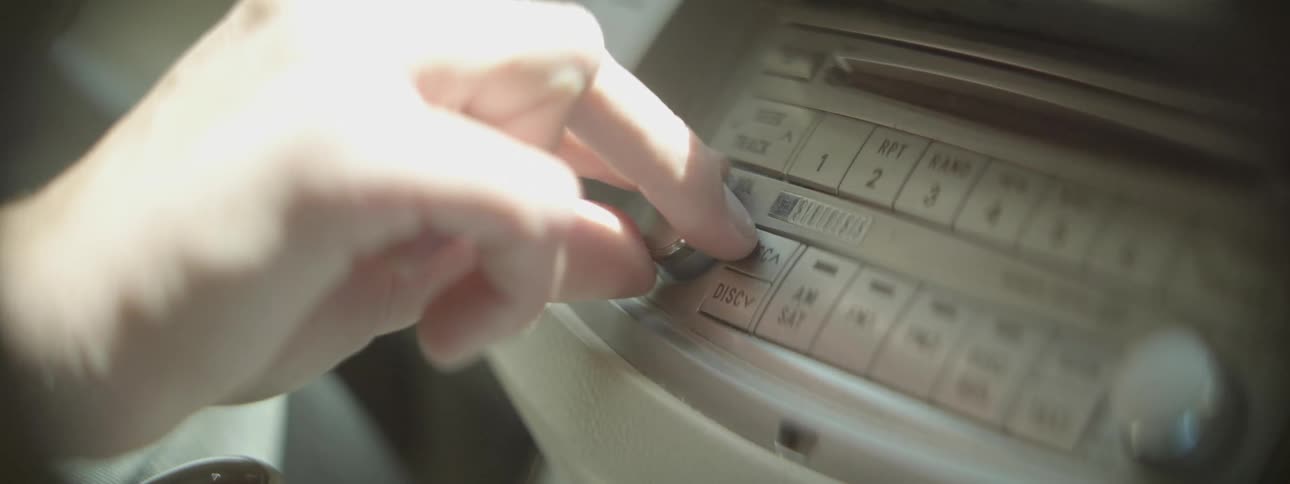 Person turning up volume on car stereo