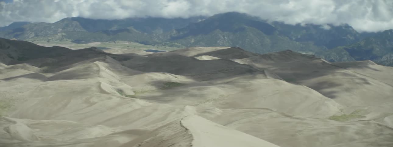 The sand dunes lead to mountains ahead