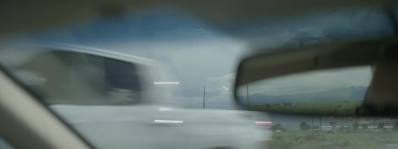 A car is moving along a busy road near a field