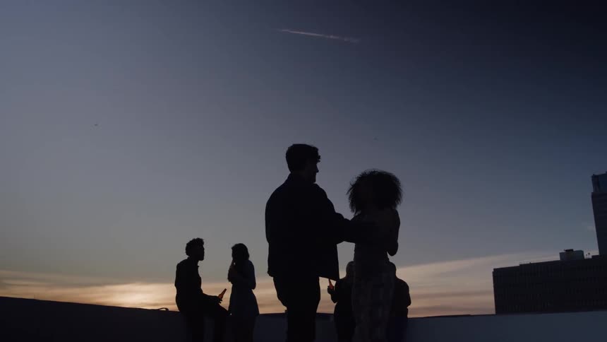 At sunset a young man and a young woman dance outdoors holding hands