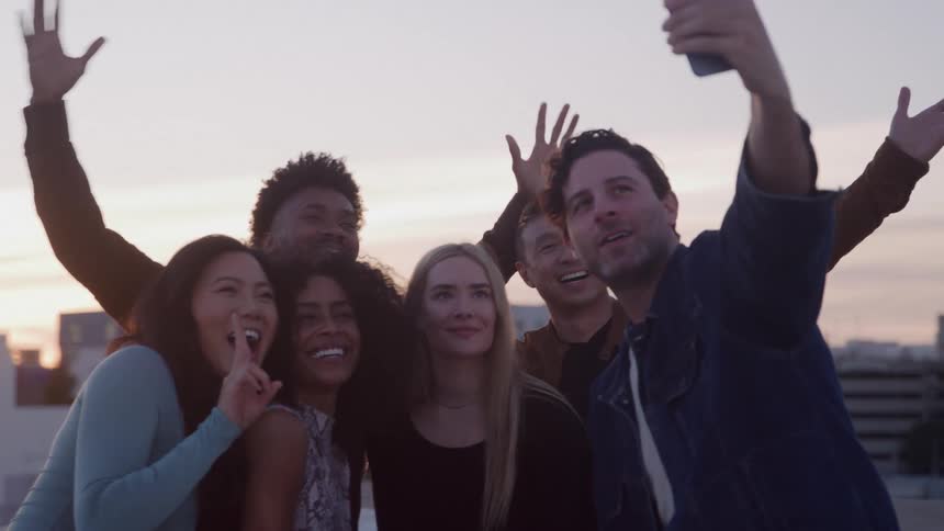 Happy friends laughing and posing taking a selfie at sunset