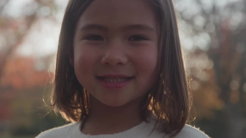Young girl smiles while standing outdoors on an autumn day