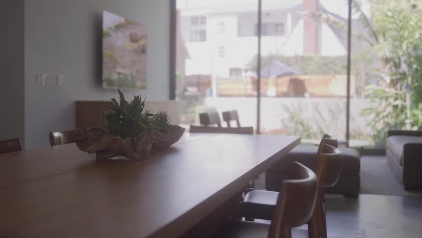 Sunlight streams onto a wooden table and chairs in a modern dining room