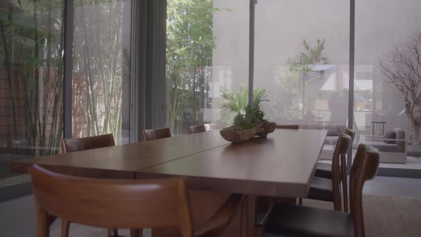 Modern dining room with wooden table and glass wall overlooking a bamboo garden