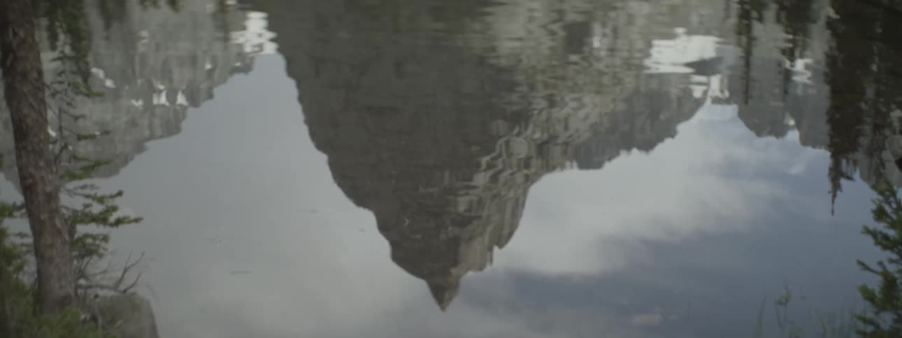 Reflection of mountains and trees on rippling lake water