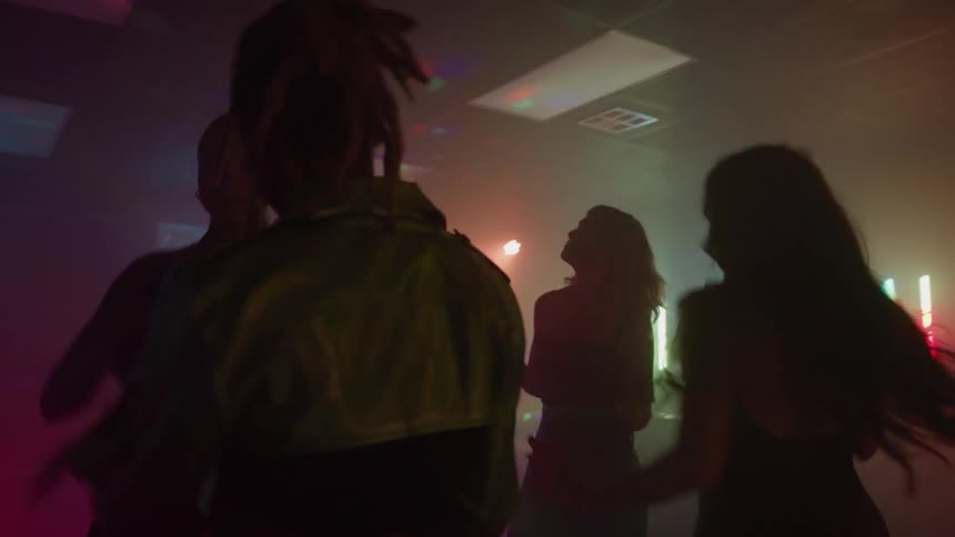A group of young adults dancing and partying in a club at night