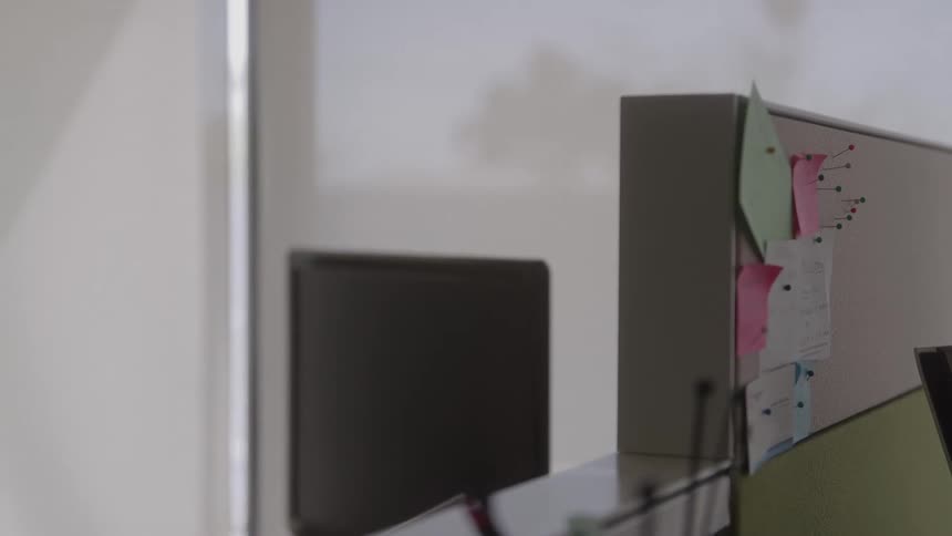 Pins hold notes on a cubical wall in an office during the daytime