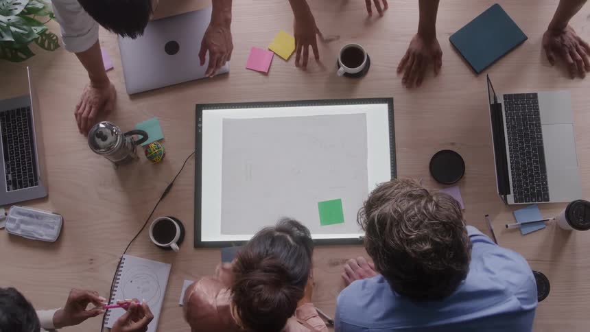 Professionals gathered around a lit table reviewing a document in an office