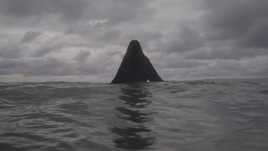 A woman stands in the ocean