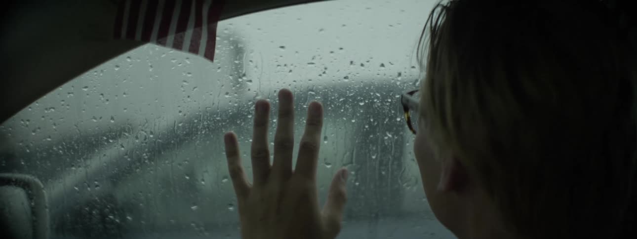 Person looks out the window of a car at the rain