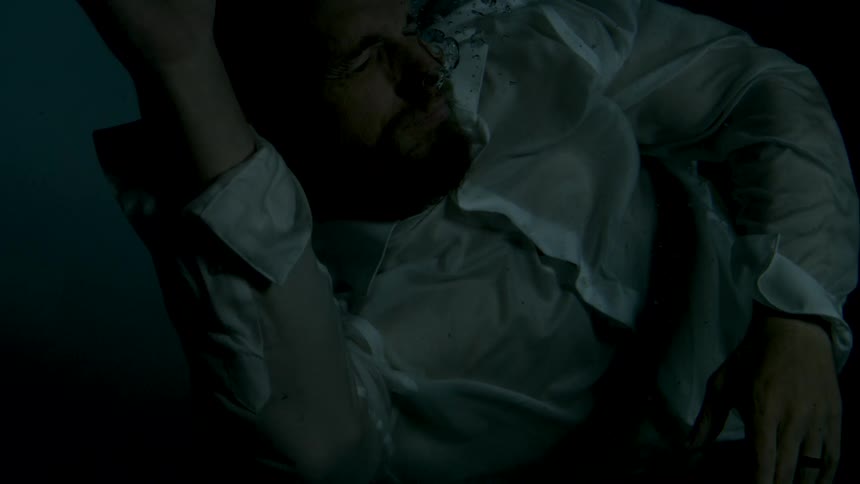 A man is submerged underwater at night struggling to stay afloat