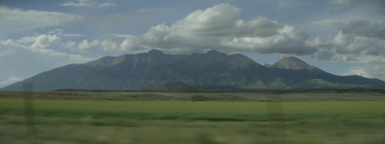 View of a field and mountains on a cloudy day