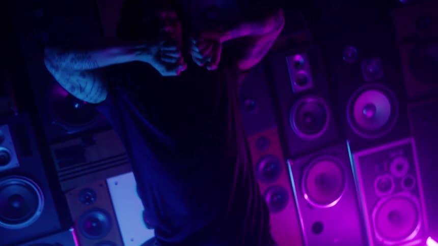 The man dances in front of stacks of speakers