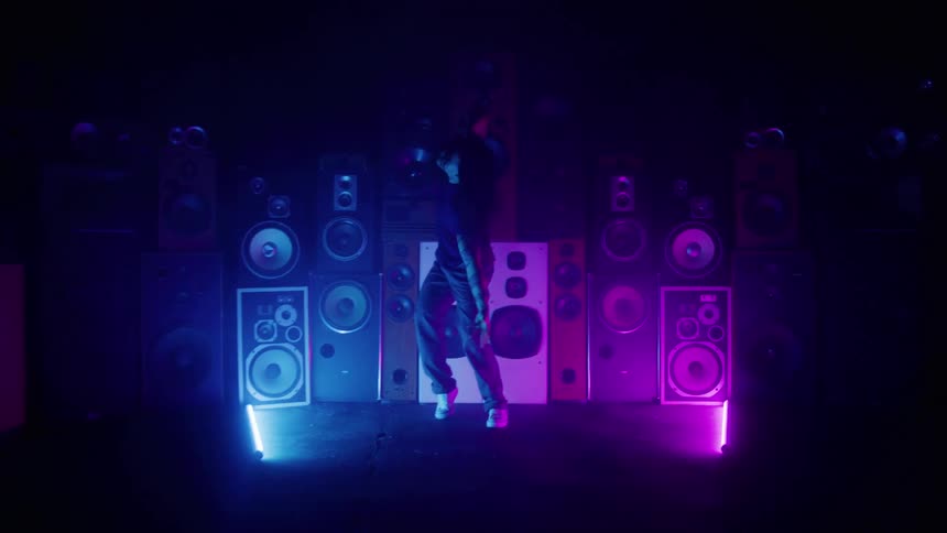 Male dancer performs on a stage decorated with a wall of speakers