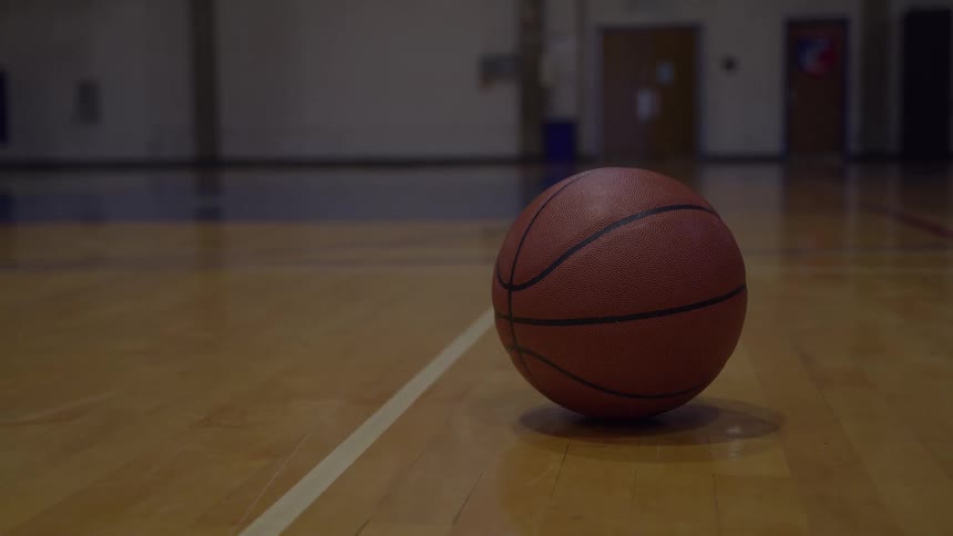 The basketball sits on the floor of the court