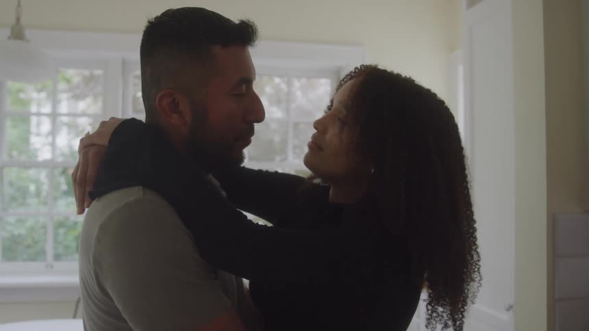 Couple embracing closely and gazing at each other in a softly lit room
