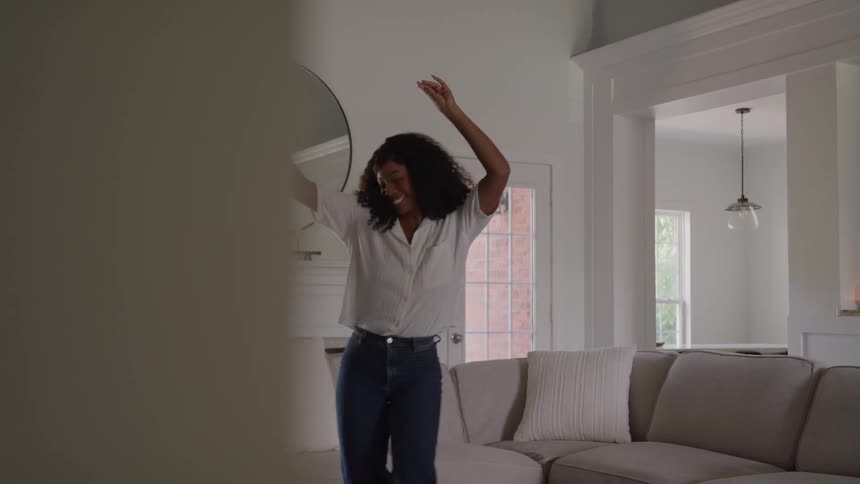 Smiling woman dances in her living room during the daytime