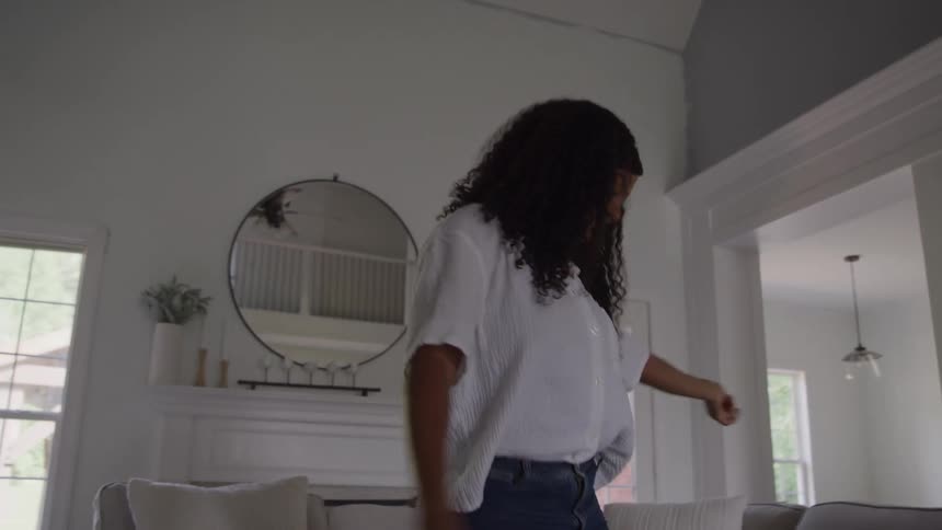 A woman dances joyfully in a bright modern living room