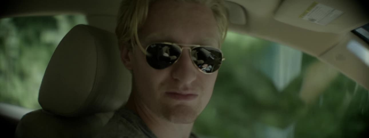 A man is riding in a car wearing sunglasses