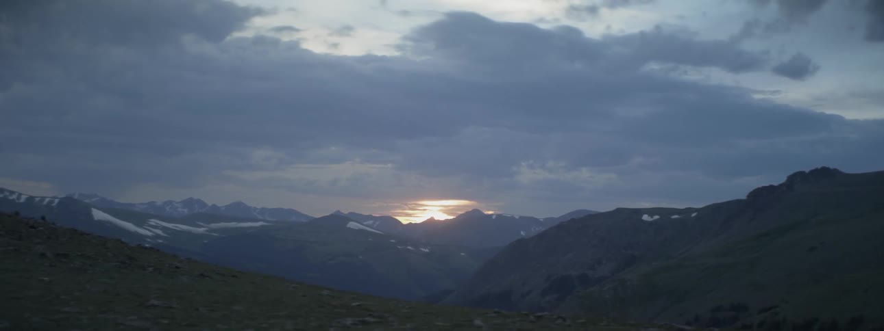 View of mountains and sun peeking through the clouds