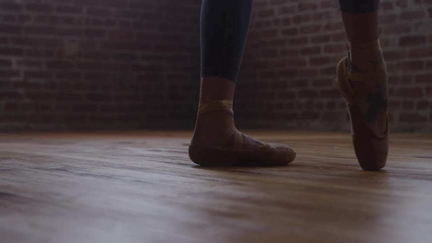 Ballerinas feet en pointe on a wooden floor