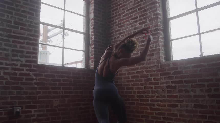 Person stretching their body in front of a brick wall and windows