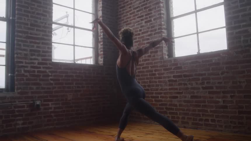 The woman does ballet near the brick wall