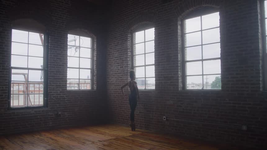 A young woman in a ballet studio dancing ballet