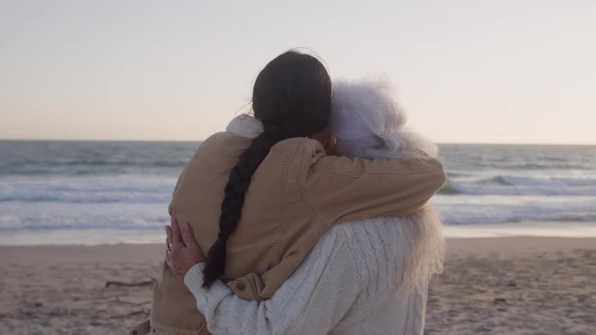 The woman look at each other and smile while hugging