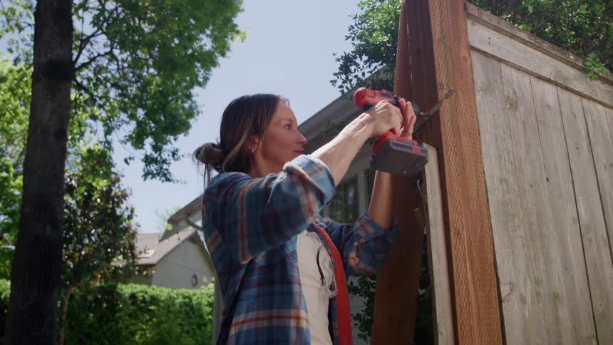 The woman is repairing her fence
