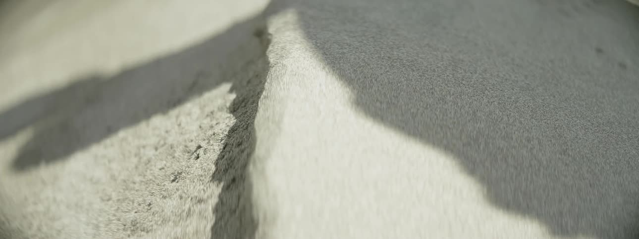 A person casts a shadow on the sandy ground
