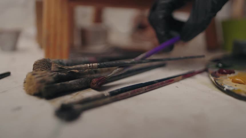 Used paintbrushes rest on the artists worktable
