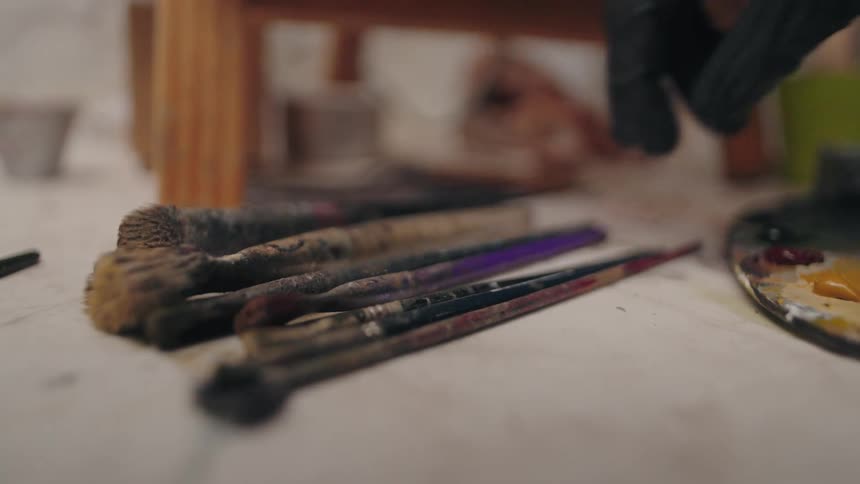 A person lays a paintbrush down with other brushes