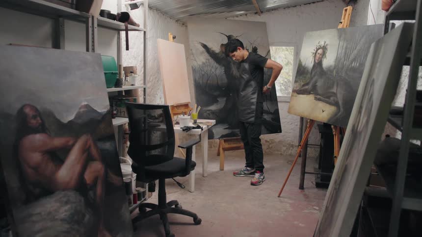 A male painter ties his apron in an art studio getting ready for creative work