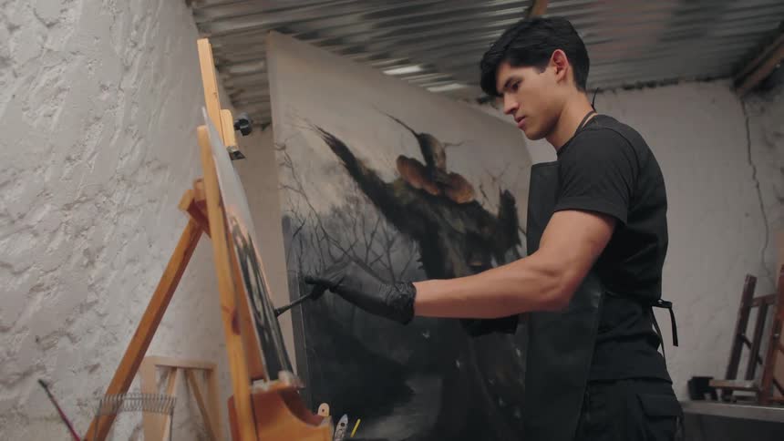 The man is painting on the canvas