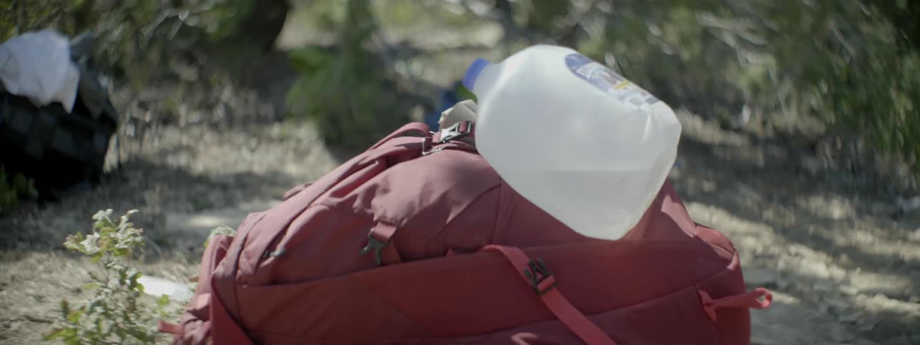 A backpack with a water jug lay on the ground