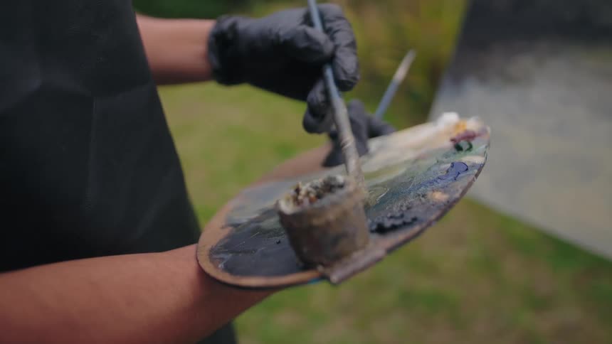 The man is mixing paint on his paint palette
