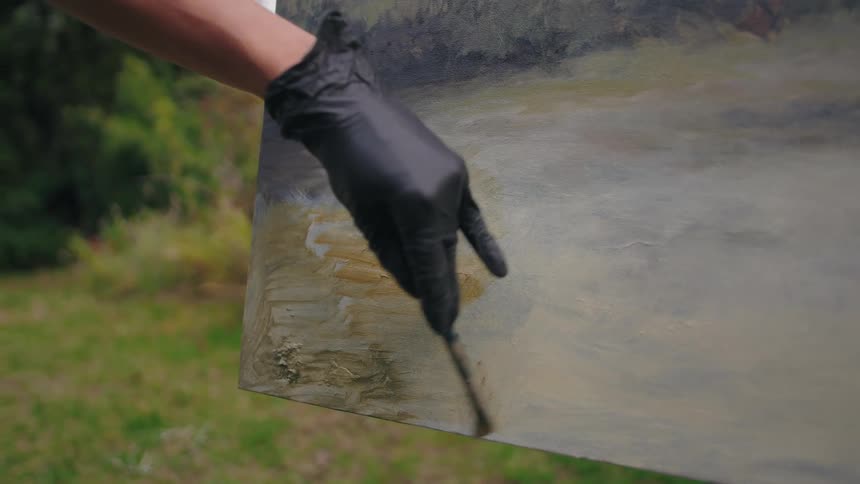 An artist paints on a canvas set up outdoors in a sunny garden