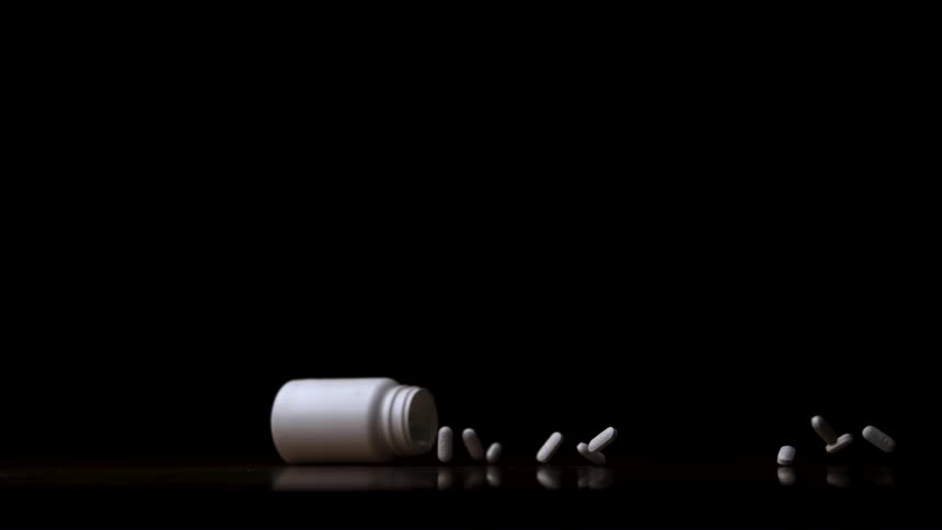 White bottle lying on the floor with pills scattered around