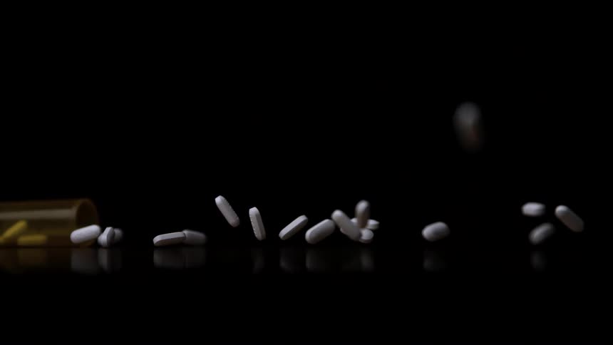 White pills falling from an amber bottle