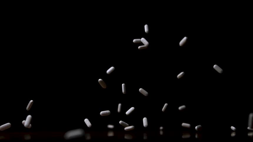 White capsules suspended in motion against a black background