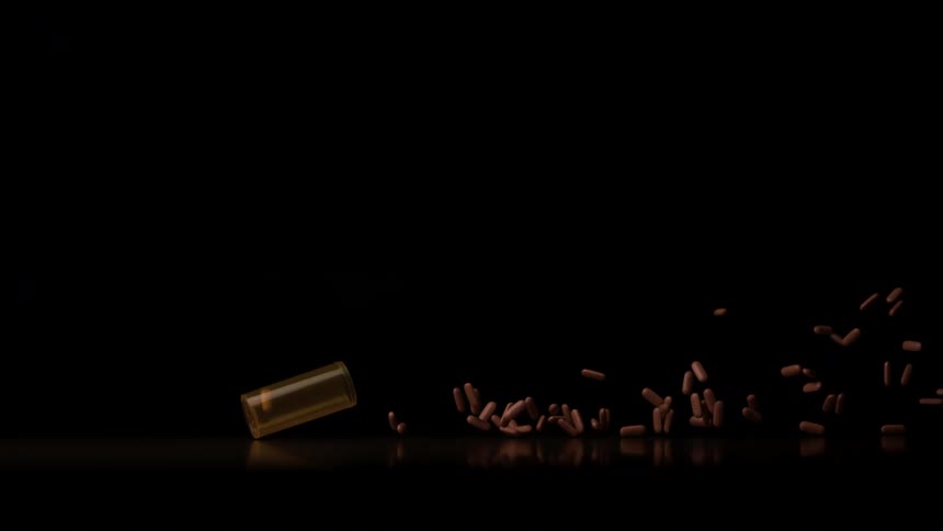 Amber bottle spills pills into the air against a dark background