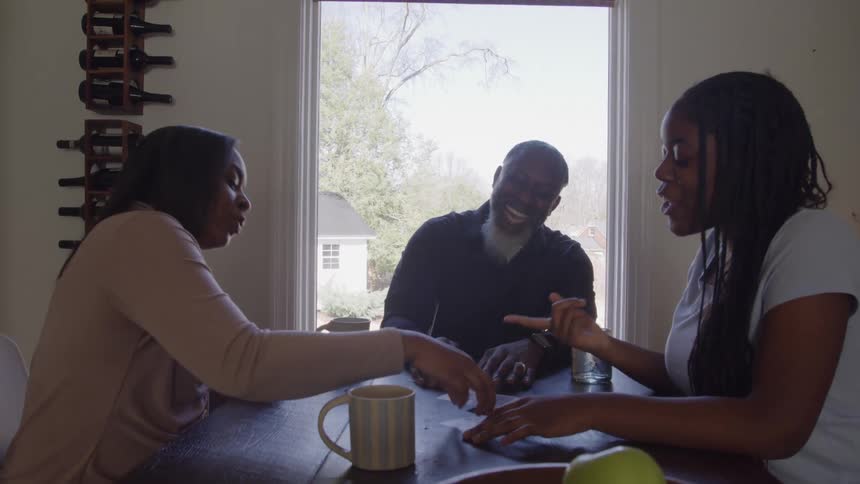 A family has fun playing a card game together at a dining table