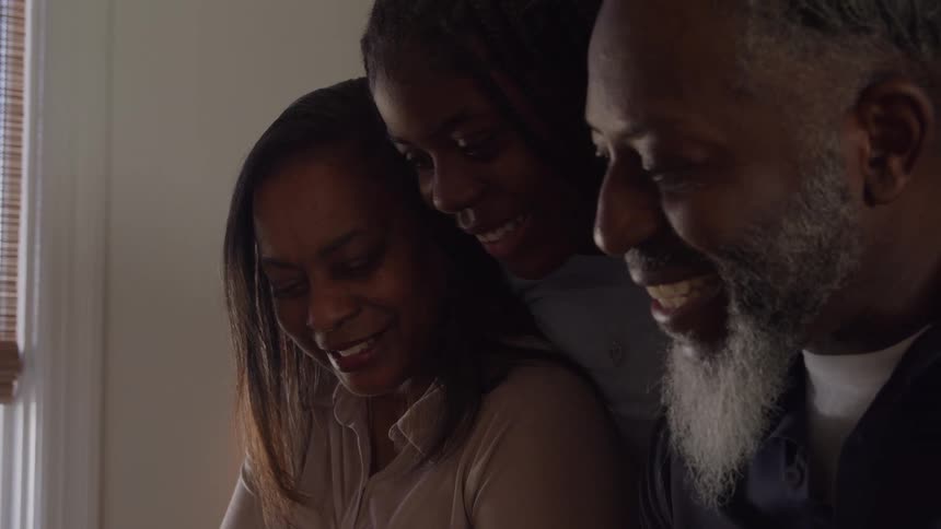 Three people gathered in a joyful intimate moment sharing smiles in a cozy setting